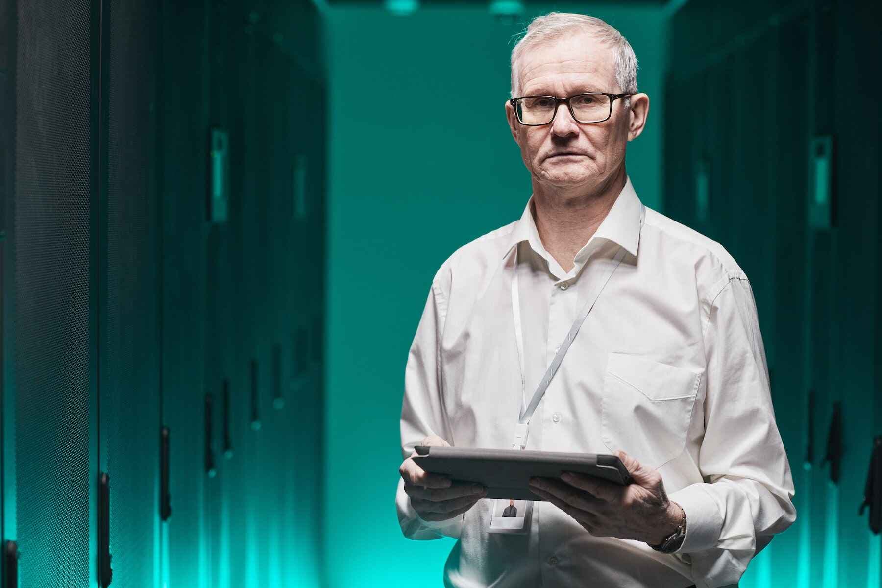 guy standing in data center with a tablet in hand