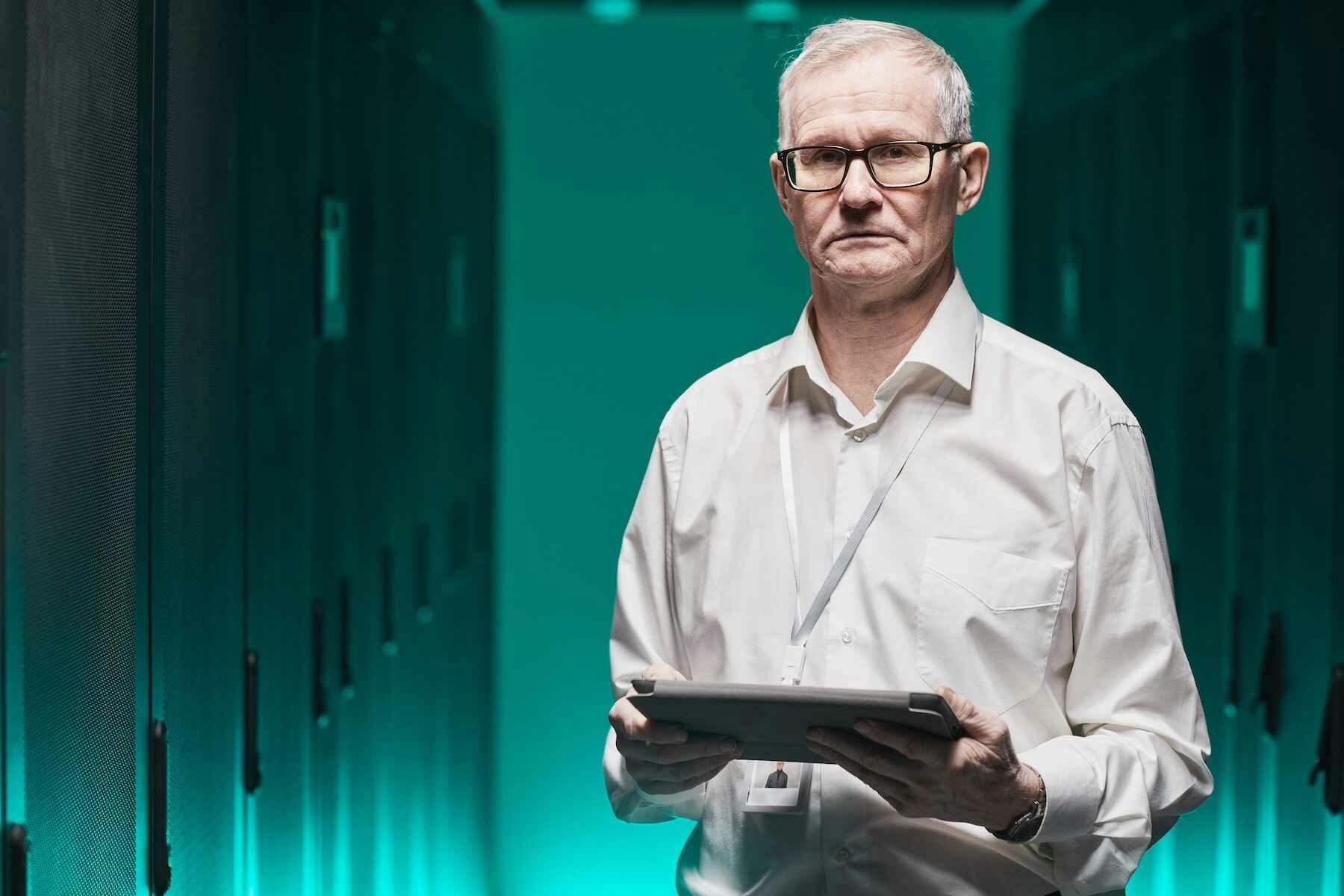 guy standing in data center with a tablet in hand